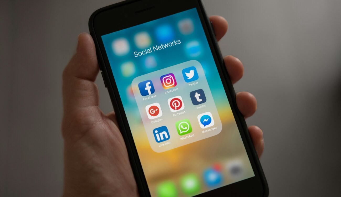 A smartphone displaying various social media icons held in a hand, showcasing modern communication apps.